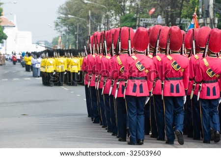 Thai soldiers parading at a street in Bangkok in colourful parade uniforms. Shallow depth of field with the first group of soldiers in focus.