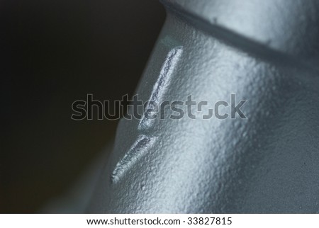 Close-up of a newly painted pipe at an industrial paint shop, with an arrow indicating the flow direction inside the pipe. Very shallow depth of field with the arrow in focus.