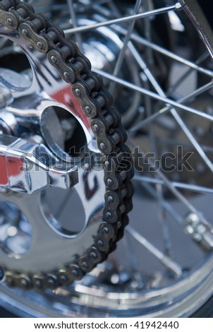 Close-up of chain on heavy motorbike with many chrome parts. Very shallow depth of field with top half of the chain in focus.