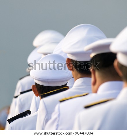 Military officers in parade uniforms seen from behind. Shallow depth of field with the short officers in the middle in focus. Photo taken in Thailand.