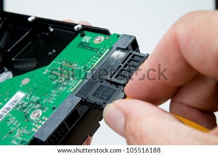 Fingers connecting serial ATA cable to a hard drive