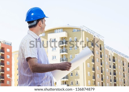 Construction manager holding project and observed on building site .