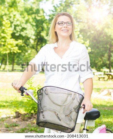 Beautiful and happy young woman with bike outdoor.