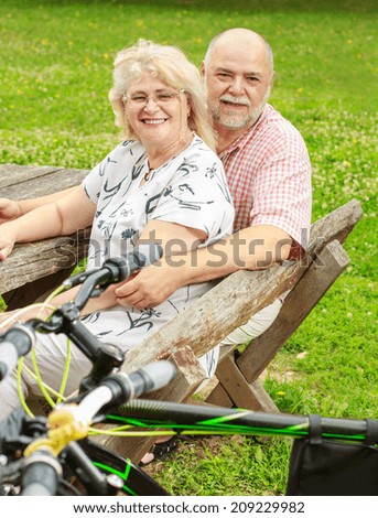 Happy elderly couple relaxing in the park after ride bike.