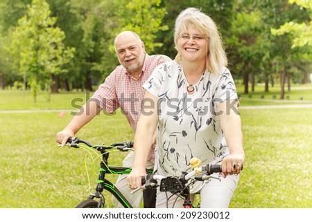 Portrait of senior woman and man ride bicycle outdoor.