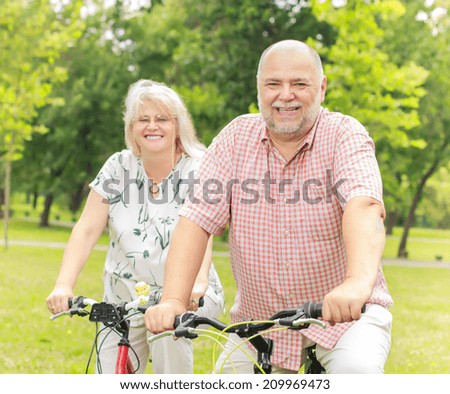 Portrait of elderly couple ride bike in the park.