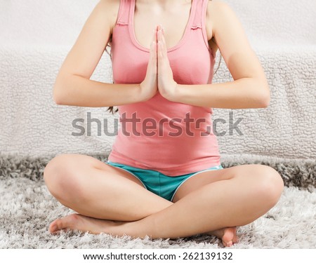 Young Woman Doing Yoga Meditating Relaxing Exercise in prayer position at home.Healthy Lifestyle.Unrecognizable caucasian female practicing meditation on the floor.