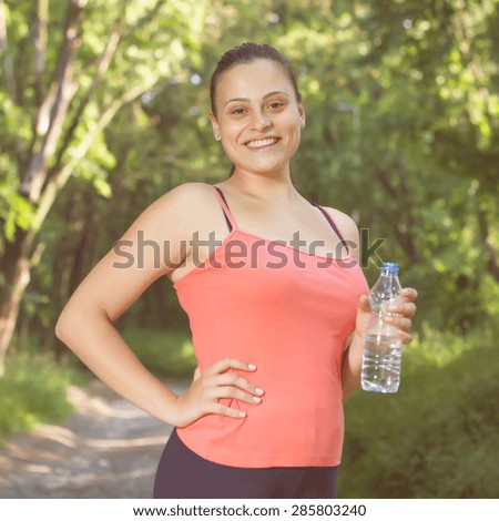 Fitness Smiling Healthy Young Woman with bottle of water outdoor,