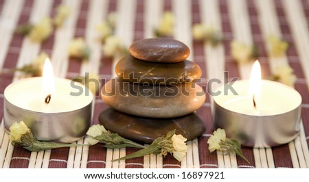 Zen like balanced stones, dried flower and candles on bamboo background.