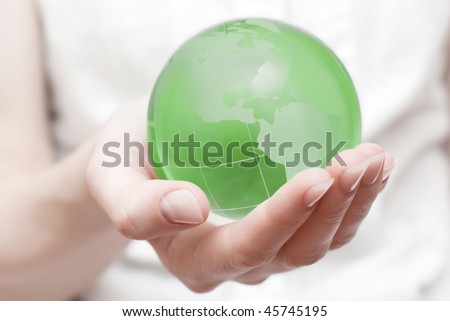 Green transparent earth globe in the hand with shallow DOF.Earth saving concept.