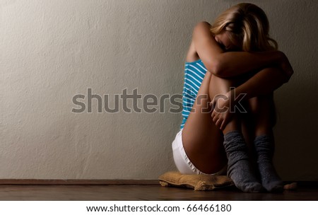 Scared woman sitting on floor.