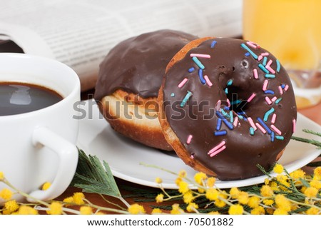 Chocolate donut served with coffee and orange juice.