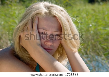 Blonde young lady sitting with head taken in her hands