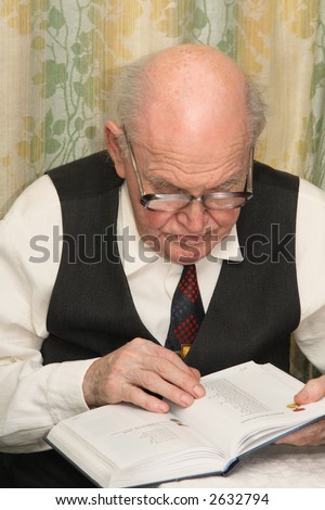 Old man in spectacles, reading a book