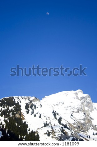 Moon rises above snowy mountains