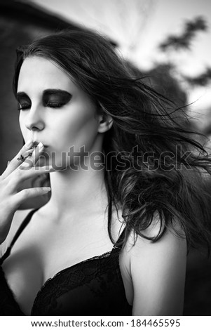 Dramatic portrait of a beautiful young girl smoking cigarette. Closeup