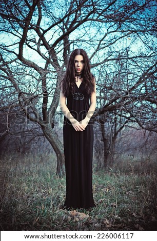 Portrait of a beautiful goth girl amongst the faded trees