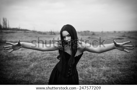 Wicked dangerous goth girl in the autumnal field. Black and white