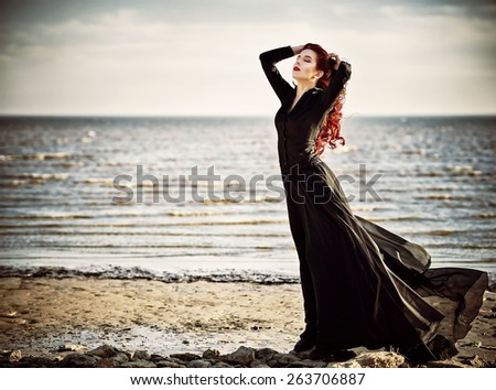 Beautiful goth girl standing on the sea beach