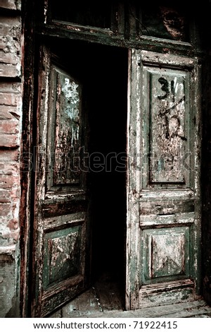 Open old door leading into a dark entrance