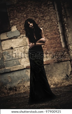 Gloomy portrait of a sick goth girl among the ruins. Low key
