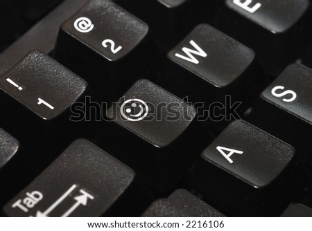 Close-up of a computer keyboard, with a smiley face on one of the keys.