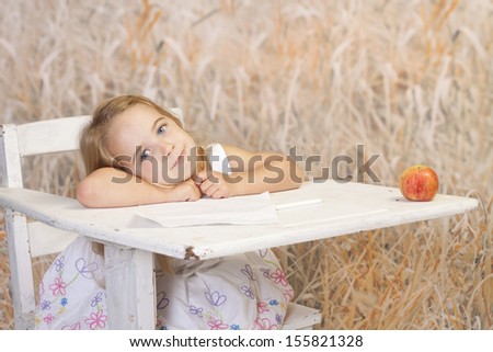 Young girl getting her education in a non-traditional way. She is sitting outdoors in a desk