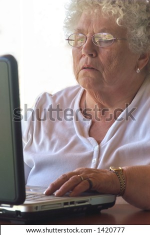 Senior woman trying hard to figure out the laptop.