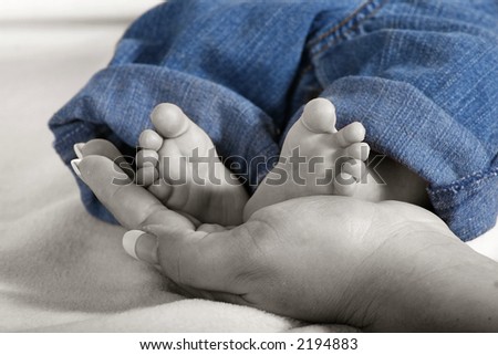 a newborn baby\'s small feet being held by mommy
