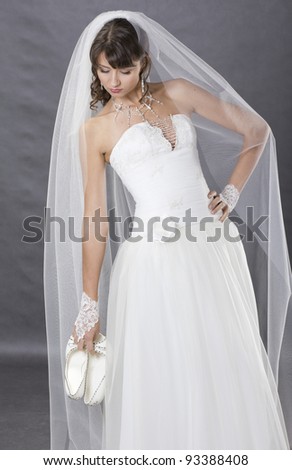 Young, beautiful bride posing in wedding clothe in studio
