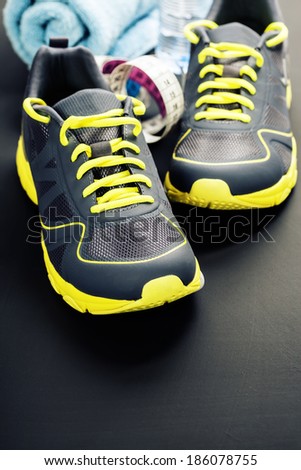 Sport shoes, measuring tape and water on grey background