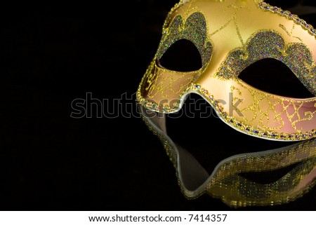 Carnival mask on a black background. The part of mask is reflected by the glass surface