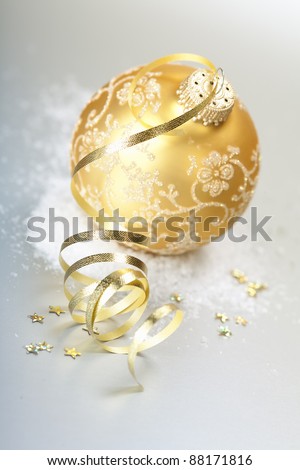 Gold christmas ball with gold ribbon bow with snow