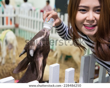 woman bottle feeds milk to goats