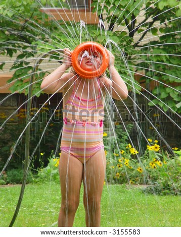 Girl with water sprinkler held on her face making a flower-like spray pattern