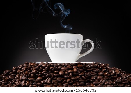 cup of coffee with a smoke on a mountain of coffee beans