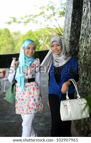 Young asian Muslim woman in head scarf walk together with handbag
