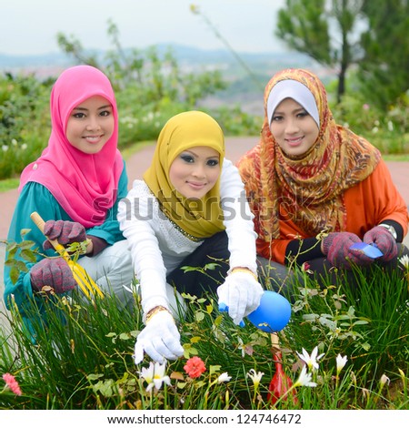 Young asian muslim woman in head scarf nursery trimming plants