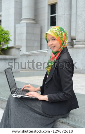 Young asian muslim businesswoman in head scarf smile surf internet