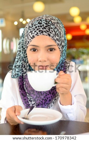 Young asian muslim woman in head scarf smile at cafe