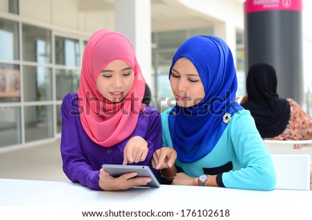 Young asian muslim woman in head scarf smile at cafe surf internet