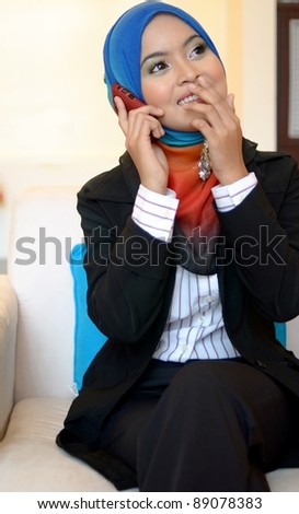 Beautiful asian business woman talking on cell phone while sitting at sofa