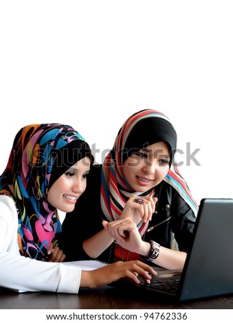 Two young pretty Asian muslim business woman in head scarf with  laptop against white background
