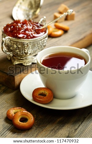 Tea with small bagels and fig jam on a wooden table.