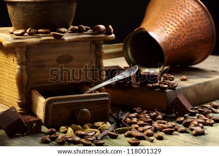 Old coffee grinder, spices, coffee beans and chocolate on a wooden table.