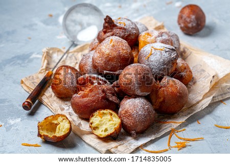Traditional French beignets doughnuts with orange zest and powdered sugar on a grey textured background, selective focus. Stockfoto © 