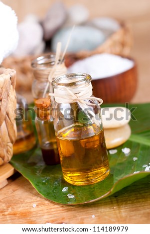 Essential oils, zen stones, salt, and green leaf over wooden surface