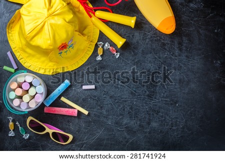 Children\'s summer yellow hat and chalk on black chalkboard from above. Summer vacation concept. Background layout with free text space.