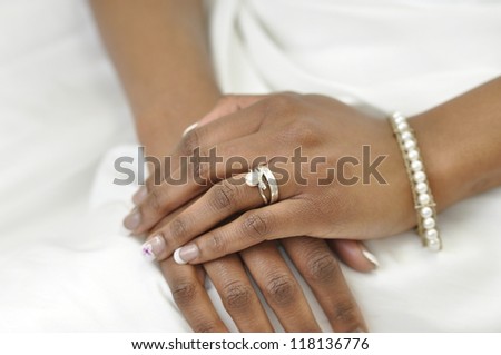hand of a young african woman wearing a wedding ring and pearl bracelet