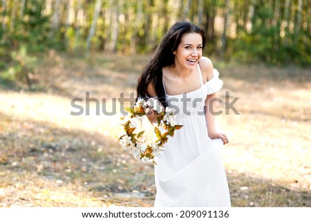 Woman in the forest with flowers in white dress